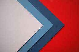 2 blue papers and a white paper against a red background