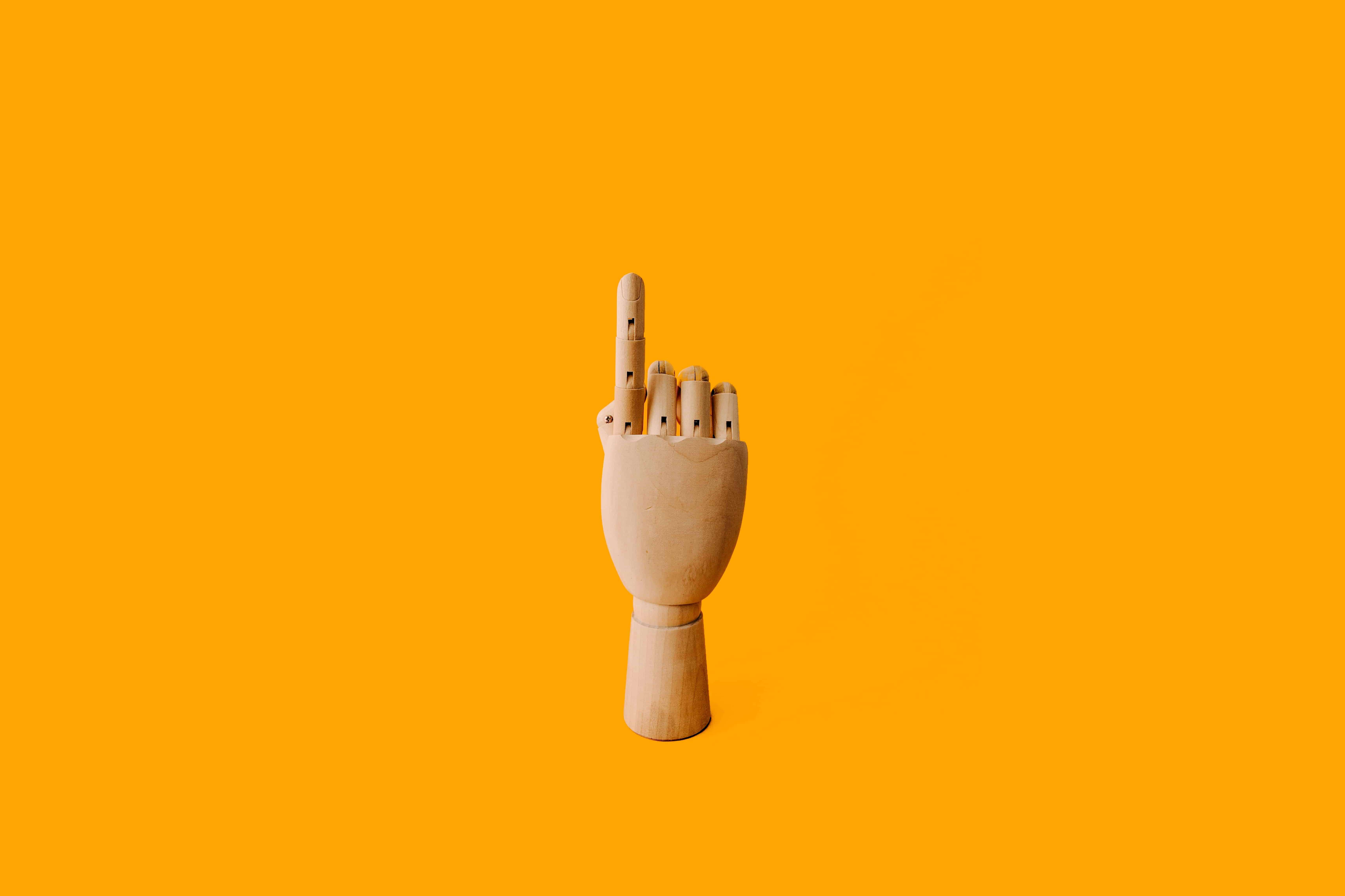 Wooden hand against yellow background