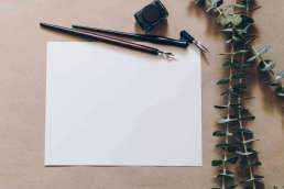 Blank paper with calligraphy pens and leaves next to paper