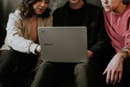 Three people looking at laptop screen