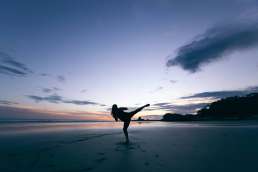 Woman practicing sparring alone on beach at sunrise