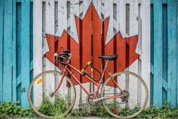 Red bicycle next to painted mural of red maple leaf