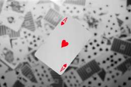 Red ace playing card with black and white playing cards in background