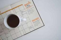 Calendar open with coffee mug filled with coffee sitting on it