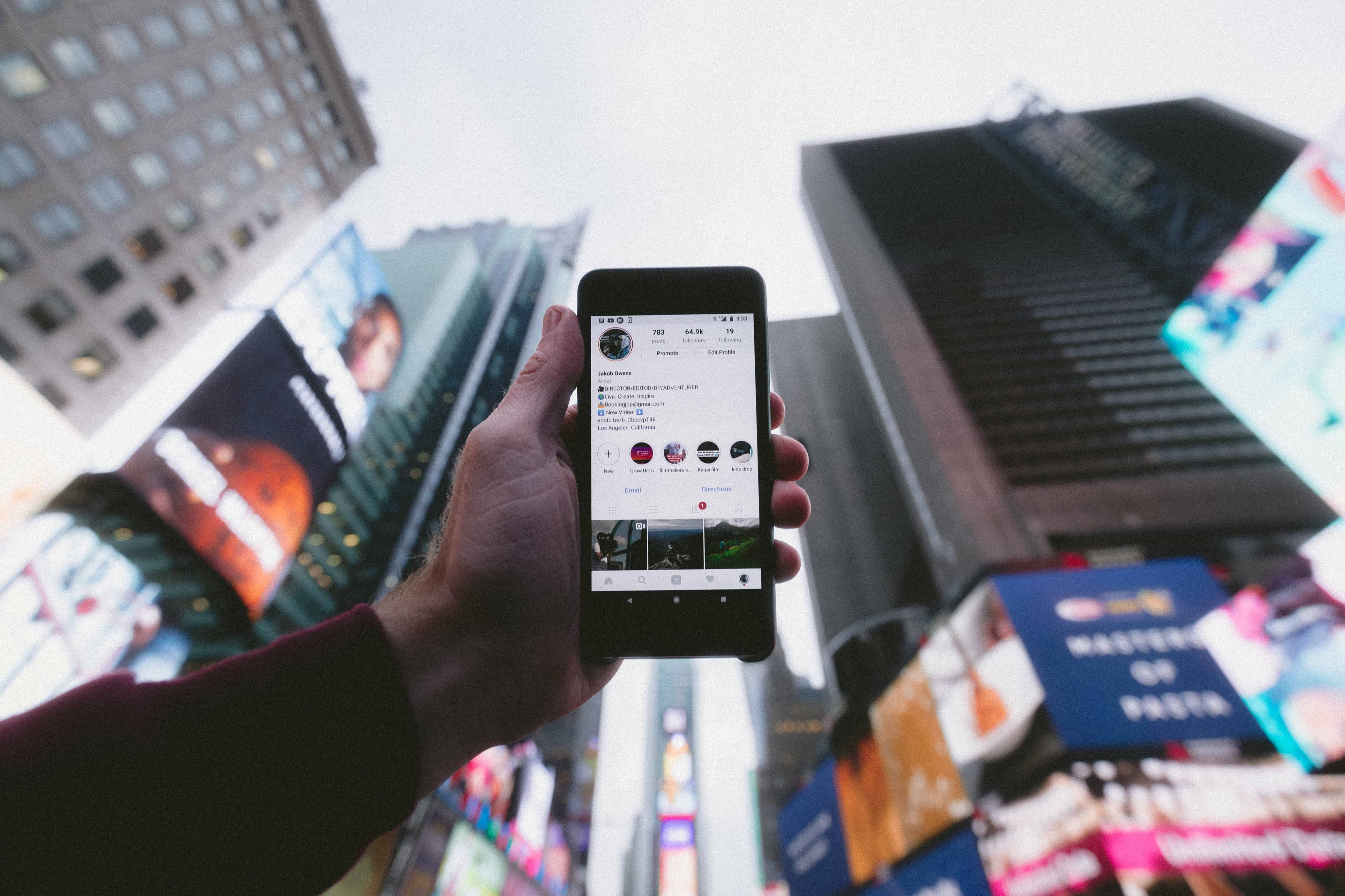 Person holding phone open to Instagram up against city background