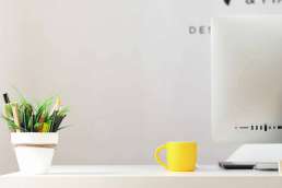 Photo of cup of pens, a yellow mug, and an Apple Desktop