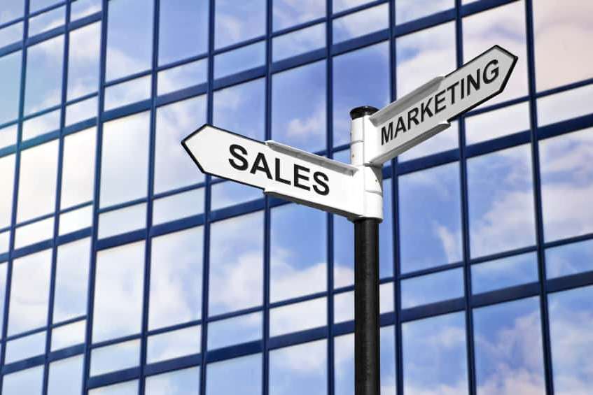 Sign saying sales and marketing against glass building