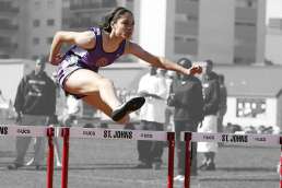 Woman jumping over hurdles with her in color and the background in grayscale