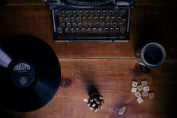 Typewriter, record, and scrabble pieces on wooden desk