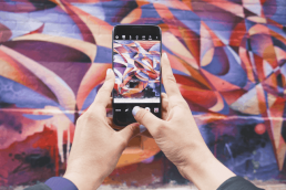 Photo of person's hands holding phone taking photo of a mural