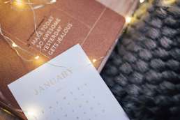 Inspirational quote and calendars against fuzzy blanket and fairy lights