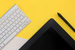 Tablet, electronic pen, and keyboard against yellow background