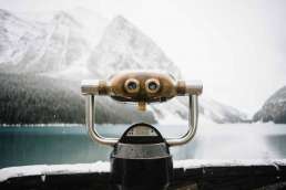 Mounted binoculars facing the snowy mountains across the lake in the background