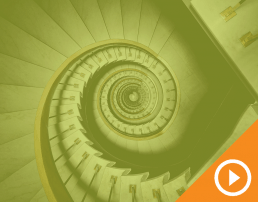 Birdseye view of a spiral staircase behind a green transparency with a white play button on an orange triangle in the bottom right corner