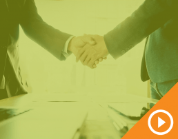 Two people in business suits shaking hands behind a green transparency with a white play button on top of an orange triangle in the bottom right corner