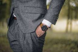 Man in gray suit with a brown watch with his hands in his pockets