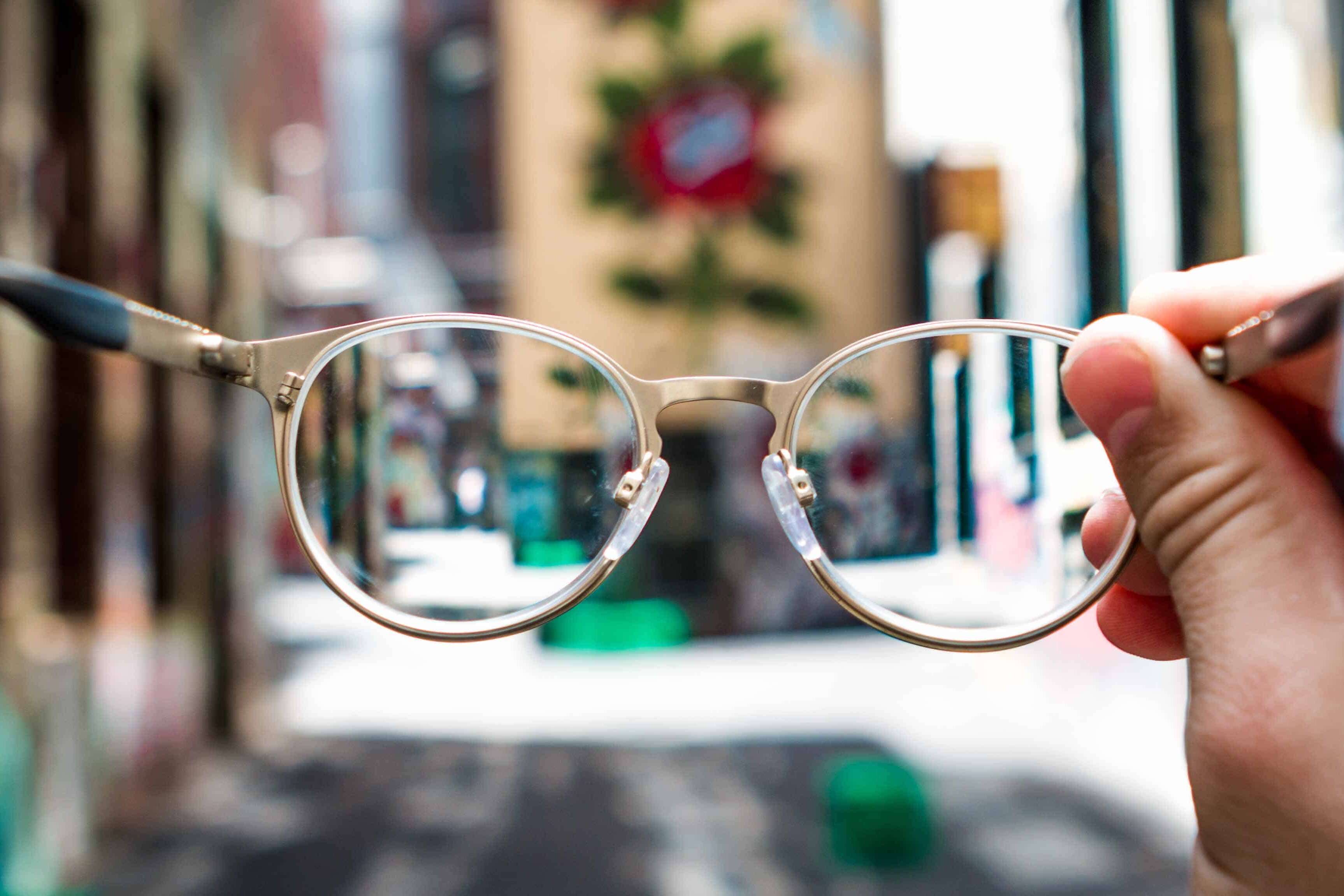 Person holding glasses with blurry street behind them