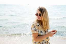 Woman holding phone with ocean behind her