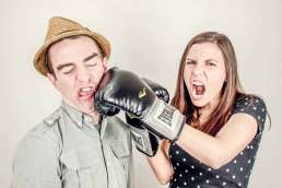 Woman punching man in the face with boxing gloves on