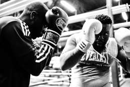 Black and white photo of two men blocking with boxing gloves