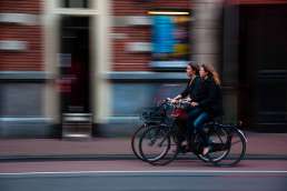 Two women on bicycles in front of a building