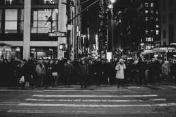 Black and white photo of crowd waiting at a crosswalk