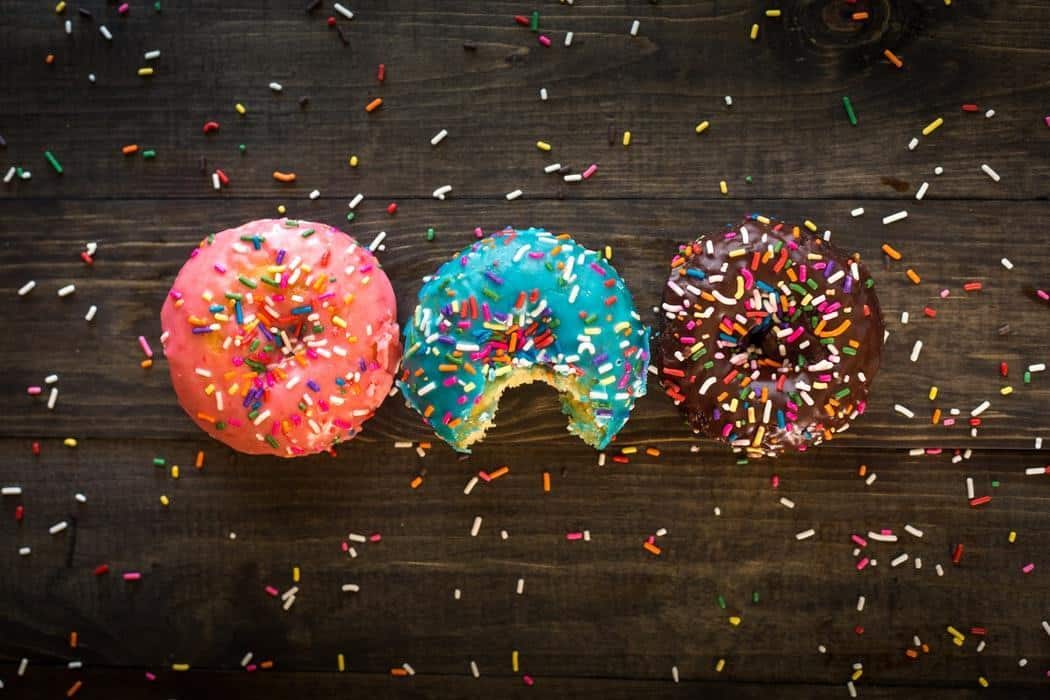 three donuts on a table with sprinkles