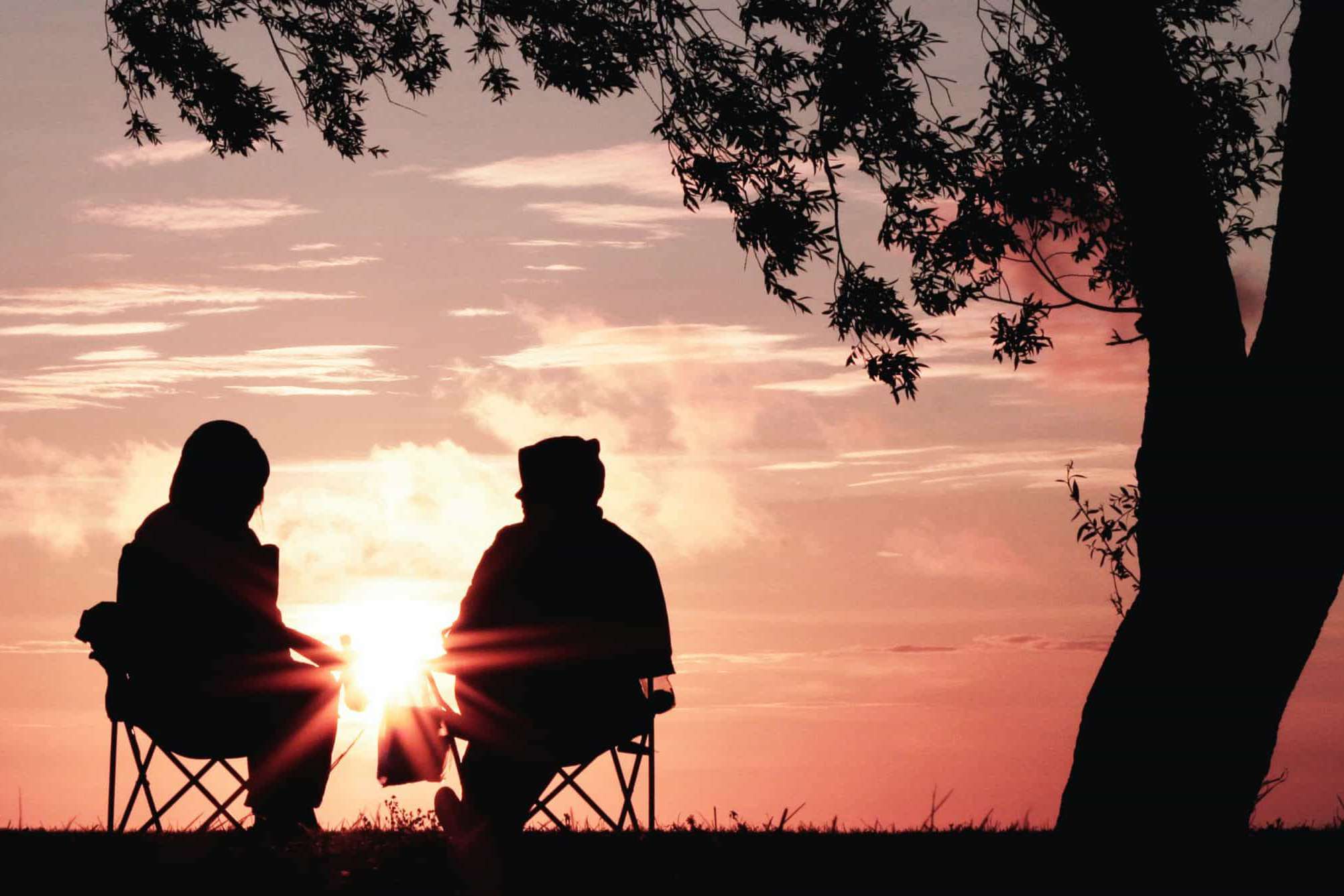 two people sat in chairs at sunset